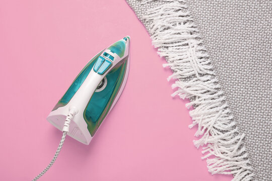 Iron and blanket on pink background. Top view