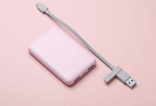 Plastic power bank with cable on pink pastel background