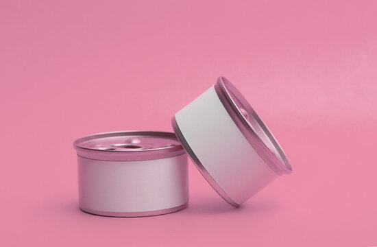 Tin cans of canned food with white labels on pink background, mockup for your design