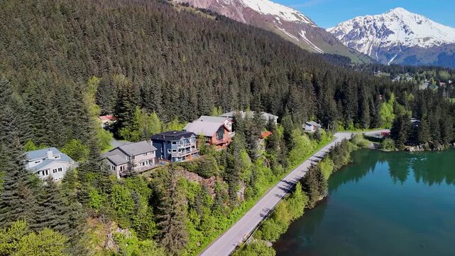 Seward, Alaska downtown sits near the shoreline bay area under a clear blue sky in summer. Boats, buildings, and mountains create a scenic coastal view. Perfect stock footage for travel, tourism, city