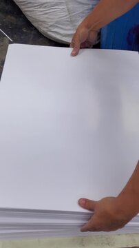 Vertical video Close up shot operator organizing large reams of blank paper stock for production in a printing factory