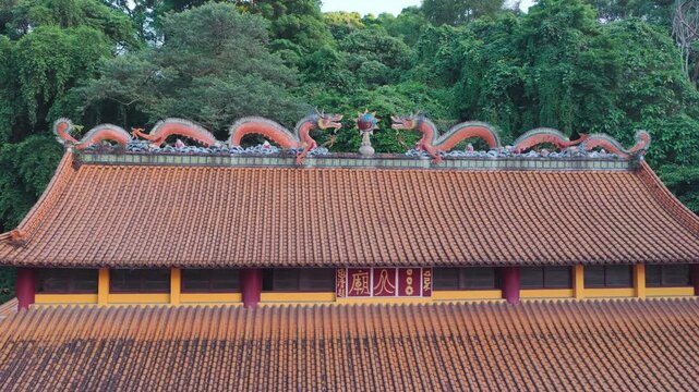 A stabilized aerial orbit view capturing the exquisite roof details of a traditional temple in New Taipei City. Two orange dragons facing a flaming pearl decorate the orange tiled ridge set against a 