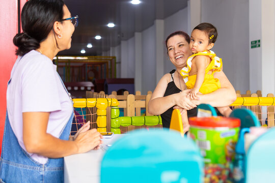 Two adult women and a baby sharing a welcoming moment at a childcare center, reflecting trust, care and family support, Latina women and baby 1 to 2 years old.