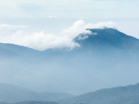 Scenic mountain forest panorama with atmospheric fog and blue natural tones suitable for sustainable travel advertising, renewable energy branding, and commercial background design.