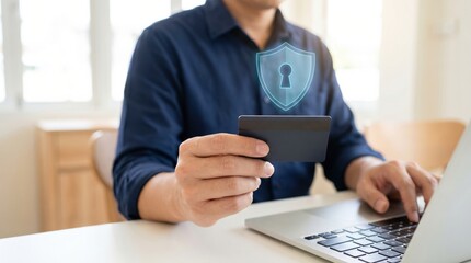 Fototapeta premium Man using a laptop and holding a credit card for secure online shopping and payment.