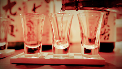 Pouring Clear Japanese Sake into a Glass Flight at an Izakaya © blueringmedia