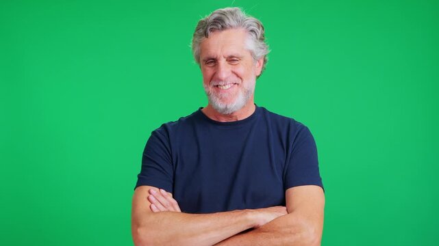 Mature confident man smiling and nodding with crossed arms on green screen background