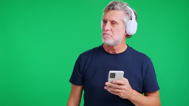 Senior man with headphones displeased by music on his smartphone