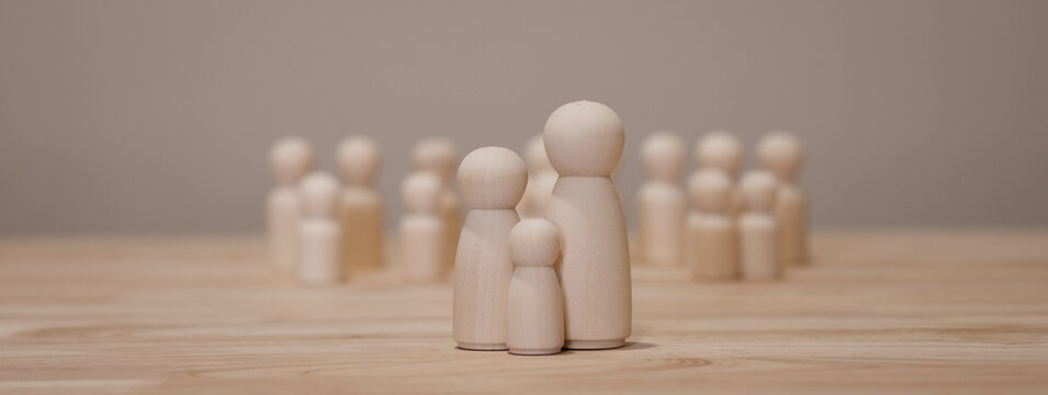 Conceptual wooden dolls forming a small family illustrating parenting responsibility, social expectations and hope parents have for their children success.