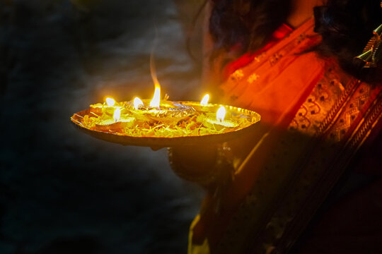 Indian woman holding a tray with Diya oil lamps light, Deepavali or Diwali celebration, Spiritual oil lamp called aarti in India on the occasion of holy ritual at home.