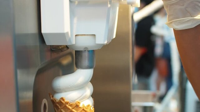 Woman's hand holding wafer cone filling soft served premium milk low fat.	Selective focus.