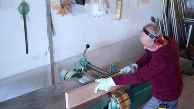 Professional carpenter planing a wooden plank with a surface planer