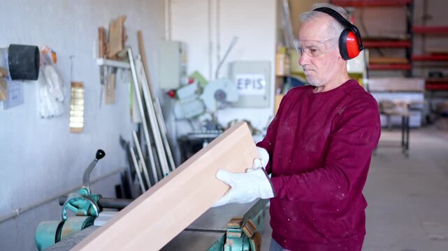 Senior carpenter using jointer machine in workshop