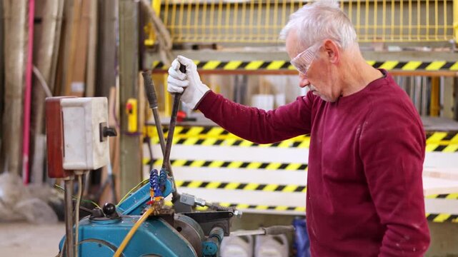 Senior factory worker threading steel bar in a workshop