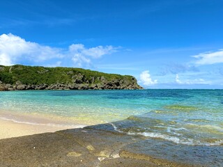 Fototapeta premium Crystal Clear Tropical Ocean and Rocky Coast Under Blue Sky, Scenic Summer Seascape with Turquoise Water