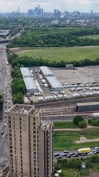 Drone hyperlapse over Eastway and New Spitalfields Market toward A12 and City of London skyline, with traffic flow, rail lines, moving trains, and fast clouds. Vertical format for social media.