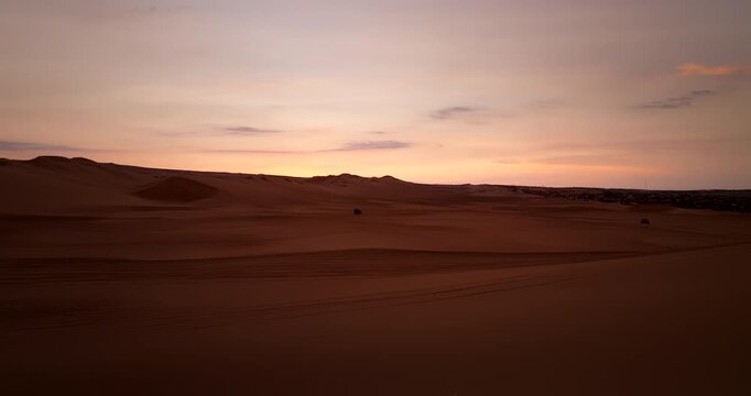 Single sand buggy on vast sand dunes of Huacachina oasis during colorful sunset in Peru. Aerial forward, copy space