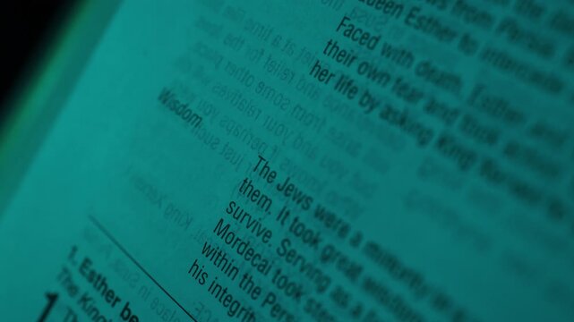 Detailed macro shot shows a Bible opened to the Book of Esther, illuminated by blue lighting. Crisp text, shallow depth of field, and artistic angle create a focused, intimate mood. Close-up shot.