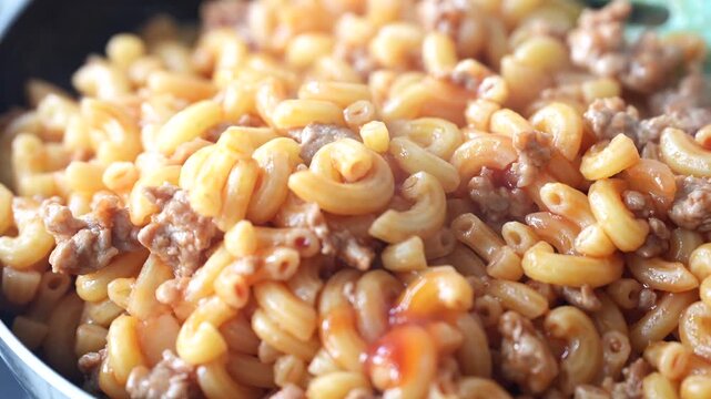 Hot macaroni stir-fried with minced meat in a pan, offering a delicious aroma and a comforting homemade meal