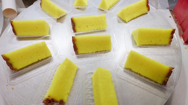 Rows of traditional Chinese yellow sponge cake dessert slices individually packaged in clear plastic containers, ready for sale at a Beijing night market, China, Asia