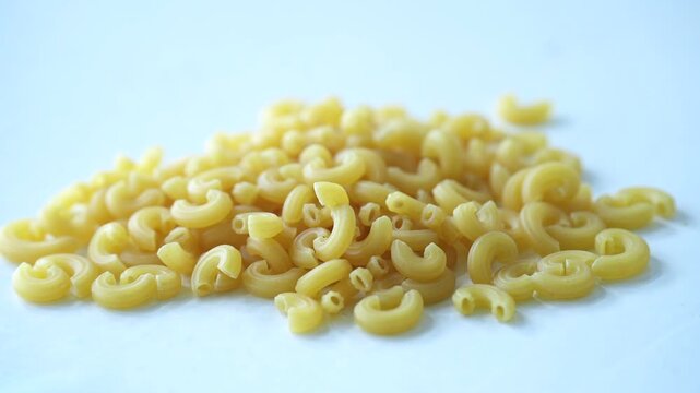 A pile of yellow macaroni pasta on a white background, creating a clean and minimal food composition
