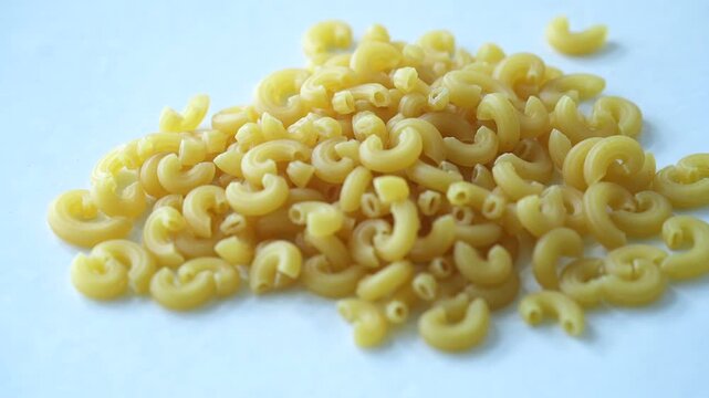 A pile of yellow macaroni pasta on a white background, creating a clean and minimal food composition
