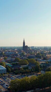 Vertical video. Strasbourg, France. Notre-Dame Cathedral, its solitary Gothic spire rising 142 metres above the Alsace plain, panoramic Drone footage on a clear summer morning. Drone footage