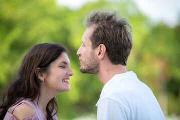 Fototapeta premium Affectionate man kissing woman forehead tender emotional love and trust between couple peaceful romantic gesture in outdoors. Happy couple sharing gentle intimate moment in garden.