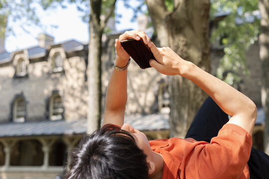 Young Man Looking at Smartphone Outdoors on University of Toronto Campus
