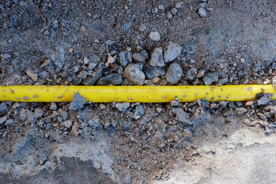 ​Yellow gas pipe underground in a trench during construction, high-density polyethylene HDPE pipeline for natural gas supply layout, utility utilities installation under concrete ground infrastructure