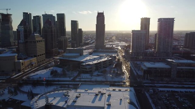 Aerial over a shopping mall in Mississauga, Ontario, Canada towards city centre, city hall and condominiums. Flying in a circular pattern with lens flare during a cold winter December day. 2021.