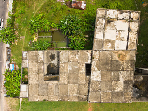Aerial view of a weathered concrete building roof with a grid pattern surrounded by lush tropical greenery and small ponds in Galle, Southern Province, Sri Lanka.