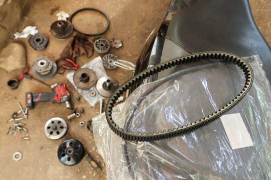 Frustrating and overwhelming scattered drive belt transmission parts for motor scooter with pulley variator clutch engine waiting for repair by mechanic in garage
