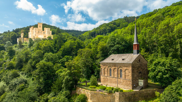 Aerial view of the historic St. Menas church and Stolzenfels Castle surrounded by lush green forests on a sunny day in Koblenz, Rheinland-Pfalz, Germany.