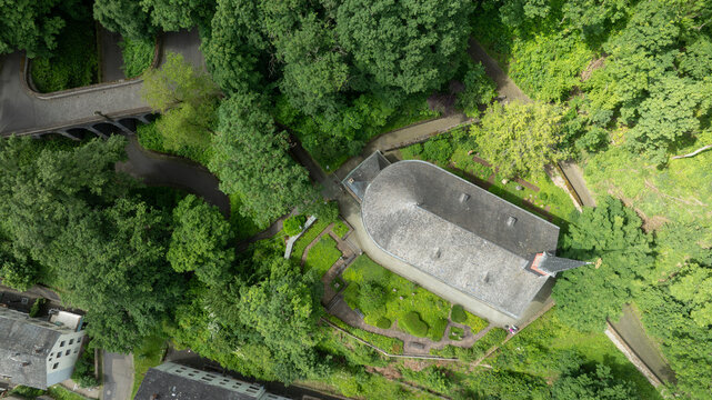 Aerial view of St. Menas church nestled among dense green trees and a winding road in Koblenz, Rheinland-Pfalz, Germany.