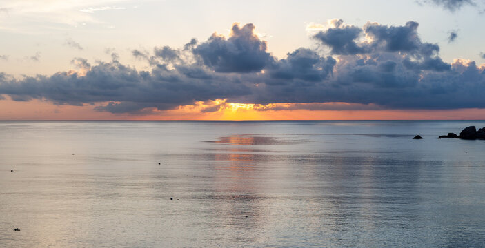 Sunrise over Ao Hin Wong bay, Koh Tao. Calm sea under a cloudy sky at dawn. Coastal landscape in Thailand. Tropical island view.