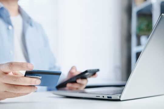 Online payment, Home office, laptop and man holding credit card and using smartphone for online payment or shopping, credit card and digital app for online banking, Ecommerce, electronic transaction