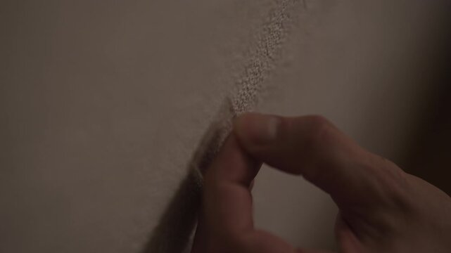 Handyman hand using finger to apply putty to fill crack in wall. Concept of simple home repair. Close-up of process covering drywall damage with filler for renovation. Shooting in slow motion.