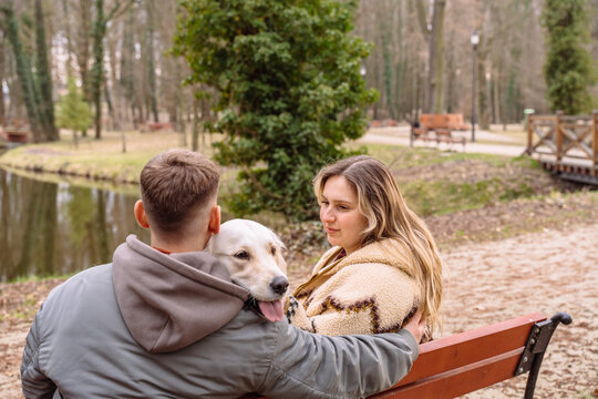 Young couple with golden retriever near modern cabin during peaceful nature retreat