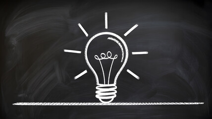 A creative lightbulb idea drawn on a black chalkboard with white chalk