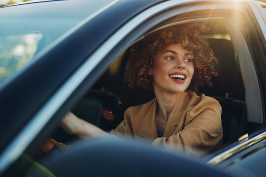 Vibrant woman driving a car, candid smile in warm retro film color, sunlit road scene, relaxed posture, casual blazer, natural tones, joyful expression, lifestyle moment