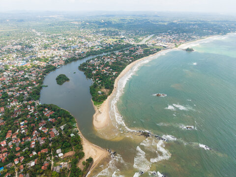 Aerial view of the Nilwala River mouth meeting the Indian Ocean with sandy beaches and urban coastal development in Matara, Southern Province, Sri Lanka.