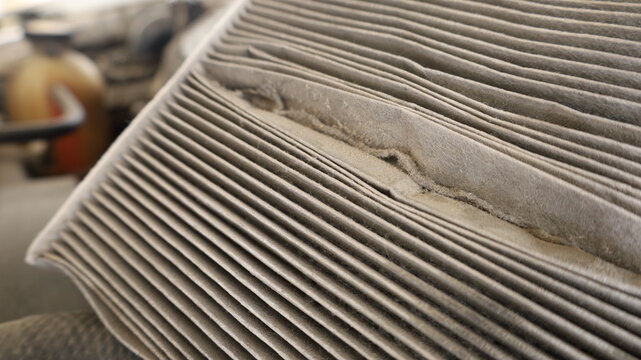 Dirty car air filter.  Close-up of the air filter of an old air conditioning system that has a lot of dust in the groove placed above the engine. Car maintenance concept with focus selection.