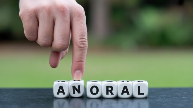 Hand changing the word ANORAL to AMORAL with letter cubes