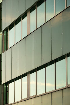 Pale facade architecture layers window rows across an urban building, with soft reflection and horizontal pattern under muted daylight