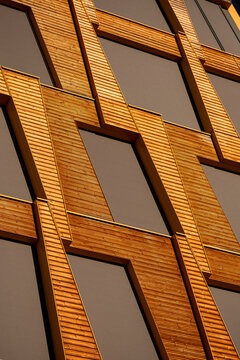 Warm facade architecture repeats window frames across an urban building, where orange texture and shadow create a geometric pattern