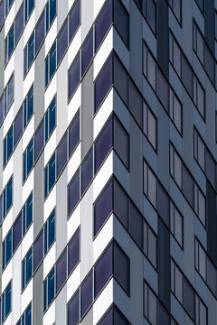 Blue tower facade architecture stacks window grid and shadow into a vertical urban building pattern, with sharp geometric lines across glass