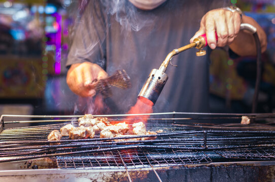 Man cooking meat on the barbecue at the night market, Kaohsiung, Taiwan