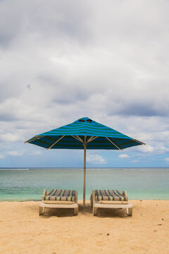 tropical beach with two sunbeds and blue umbrella