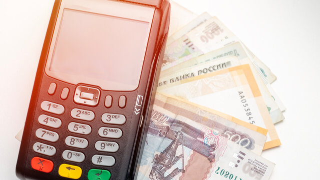 An old mobile phone rests near Russian banknotes. Its keypad and screen indicate early mobile technology. Various ruble bills display denominations. The image combines cash with outdated phone devices
